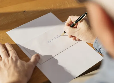 Ältere Person schreibt ihr Testament.
