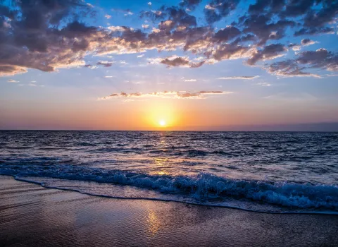Sonnenuntergang am Strand mit dunklen Wolken.